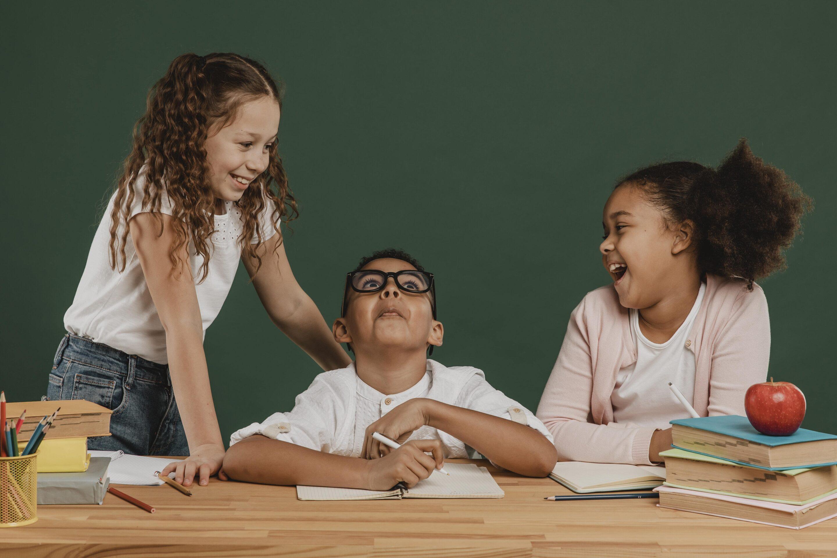 enfants qui rient en classe devant un tableau-min enfants qui rient en classe devant un tableau